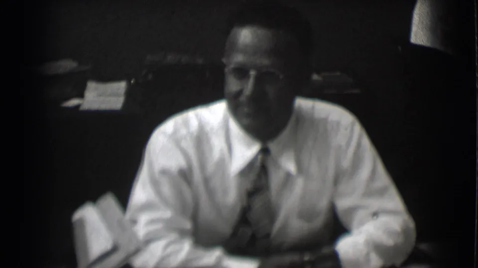 The final frame shows the seated man looking toward the camera, framed by a desk and dark office background in Saint Louis, 1959.