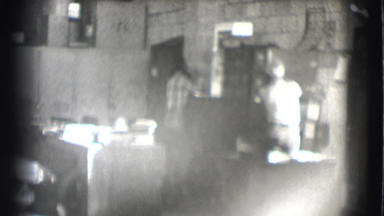 A 1959 Saint Louis office view shows a seated man at a desk with another person visible near shelves or a cabinet.