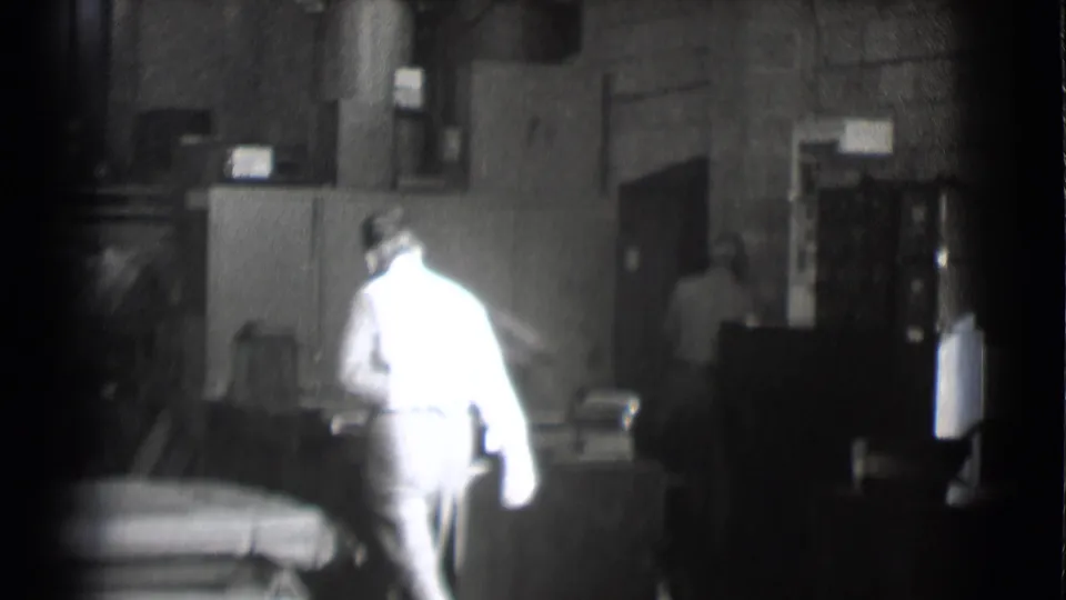 An adult man moves through a Saint Louis newsroom interior, with desks and office equipment visible in the background.