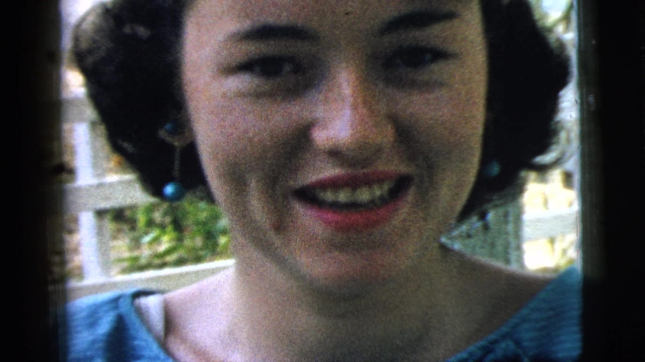 Young woman smiles at the camera with blue earrings and a white railing behind her.