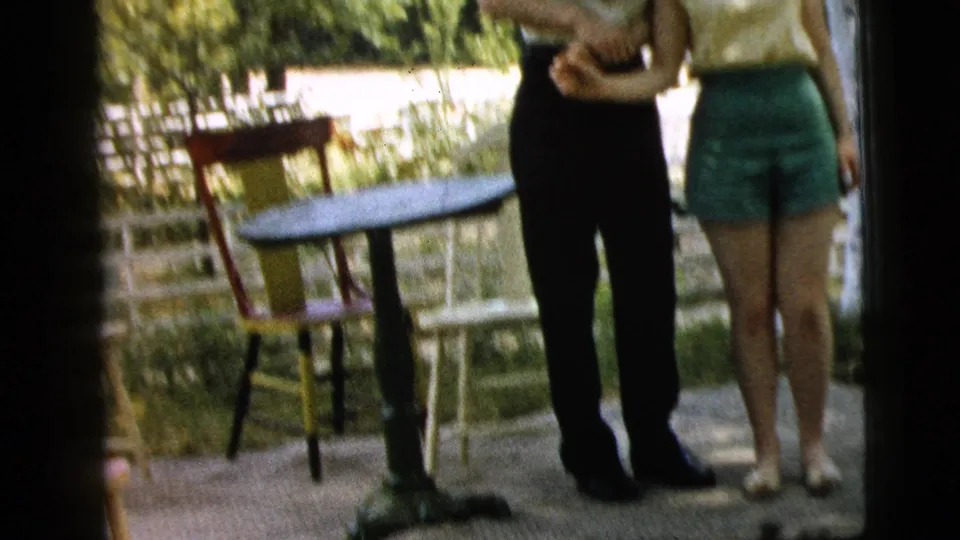 The home-movie frame shows the couple from torso to feet as they hold hands beside patio furniture in the Camden backyard.