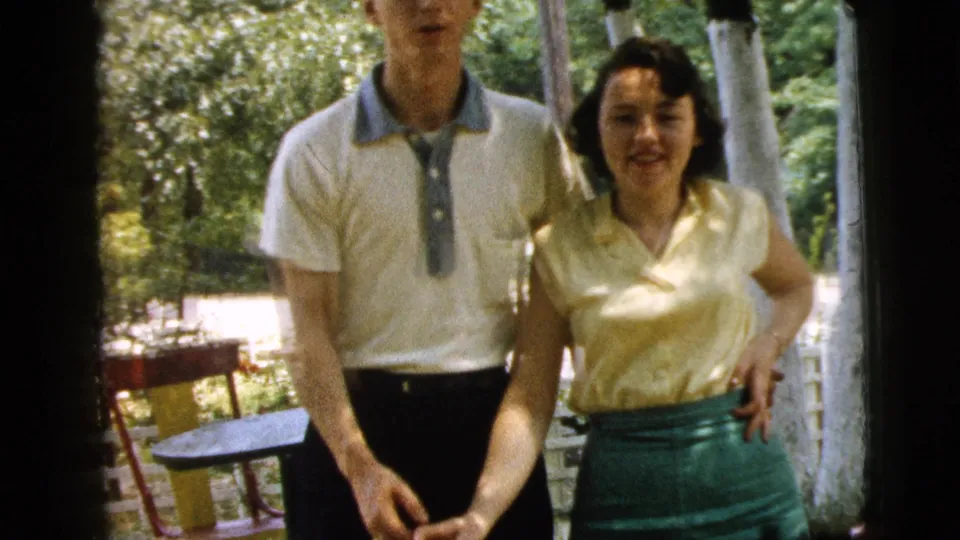 The couple faces the camera in the 1961 Camden home movie, with the woman smiling and the man partly cropped at the top.