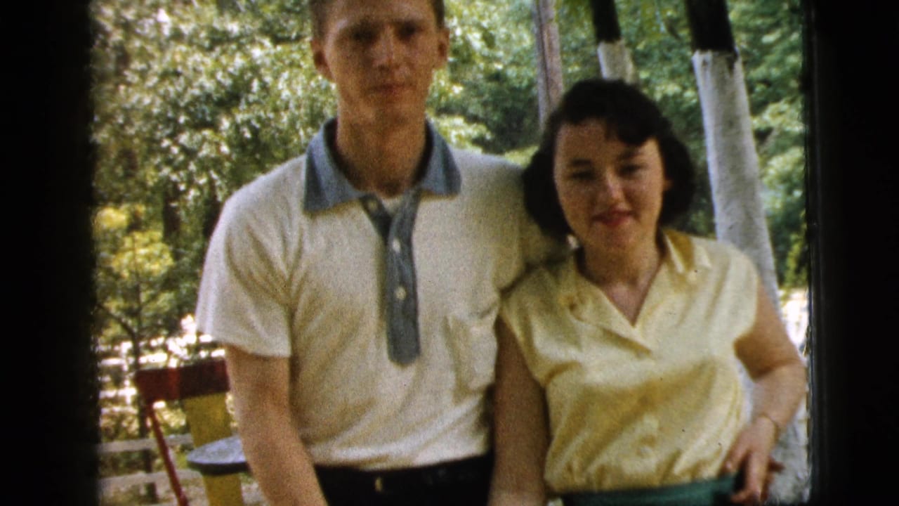Young couple standing together outdoors near trees, facing the camera.