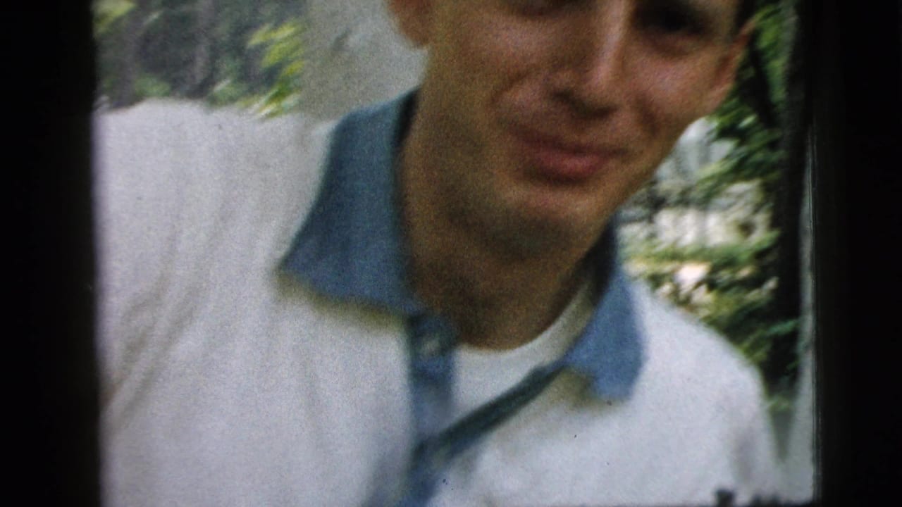 The young man remains close to the camera in the 1961 Camden outdoor scene, with soft focus and greenery in the background.
