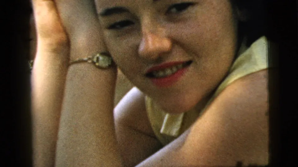 1961 Camden home-movie close-up of a young woman with dark hair leaning on her hand in soft outdoor light.
