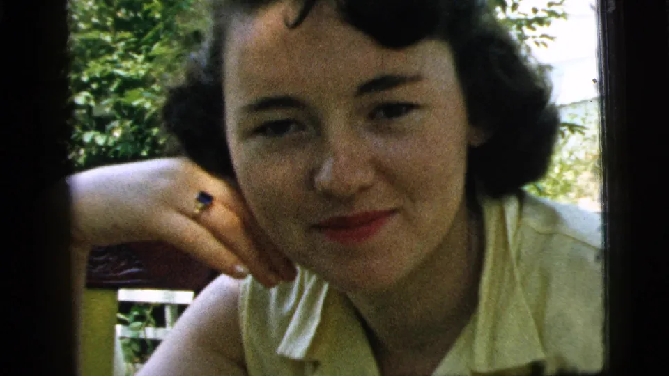 Close 1961 Camden home-movie portrait of a young woman resting her chin on her hand outdoors.