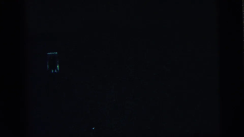 A mostly dark 8mm frame appears after the portrait, with a small light mark and faint blue-green film texture.