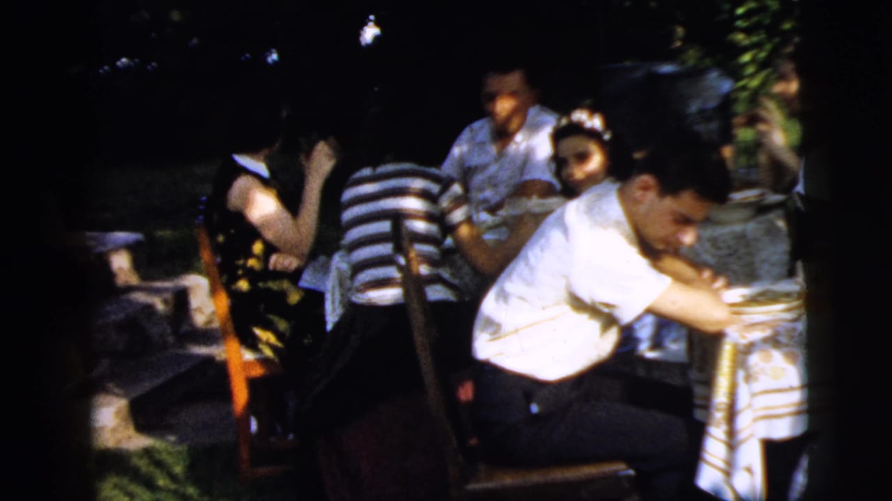 Adults seated around an outdoor table with plates and glasses in sunlight.