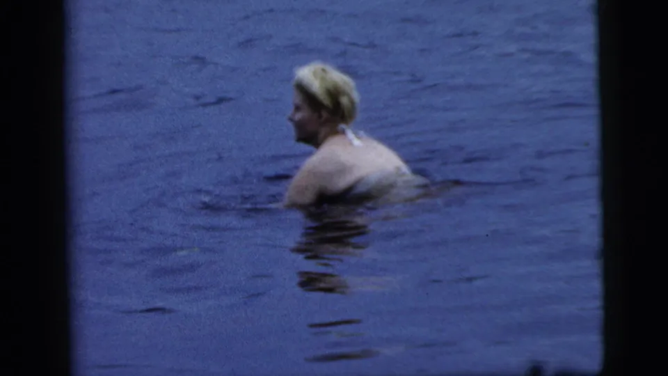 Adult woman in a patterned swimsuit turns slightly while swimming in blue water, Camden, New Jersey, 1961.