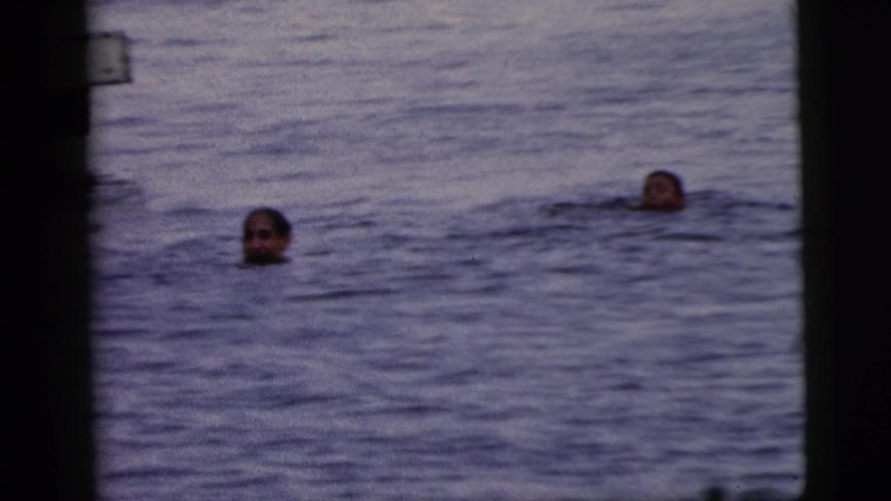 Two swimmers' heads visible above open water, framed by dark film edges.