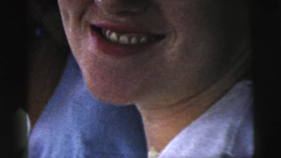 1961 Camden home-movie close-up of a smiling woman in a light collared top, with grain, faded color, and tight handheld framing.