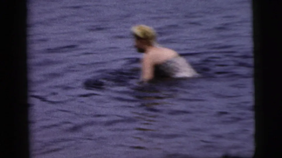 1961 Camden-area home-movie frame showing a swimsuit-clad person in blue water, with the platform mostly out of view.