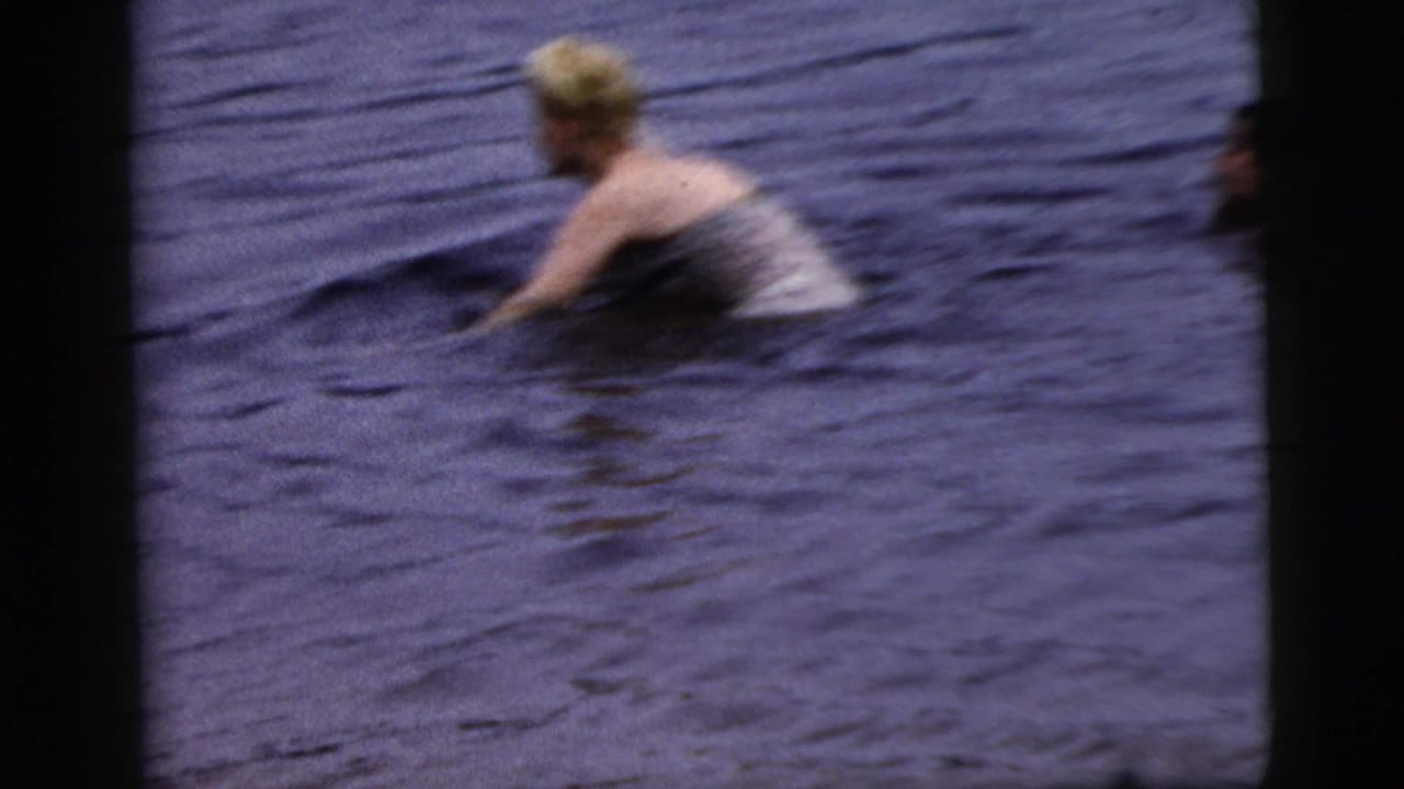 Blonde woman in light swimwear moves through dark open water.