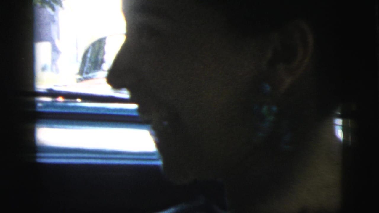 Woman in side profile seated in a dark car interior beside a bright window.