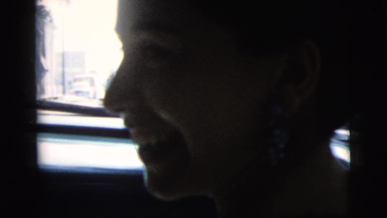In 1961 Camden, New Jersey footage, a woman sits in profile inside a car, partly silhouetted against the bright window.