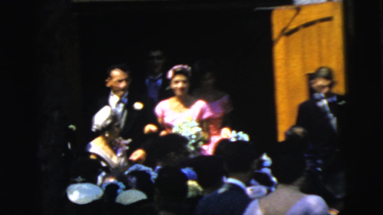 1961 Camden wedding frame with a woman in pink holding a bouquet beside a man in a dark suit at the doorway.