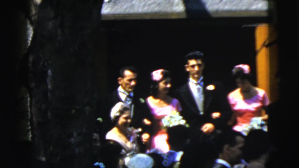 1961 Camden wedding frame with formal attendants standing arm-in-arm beside a doorway as guests fill the foreground.
