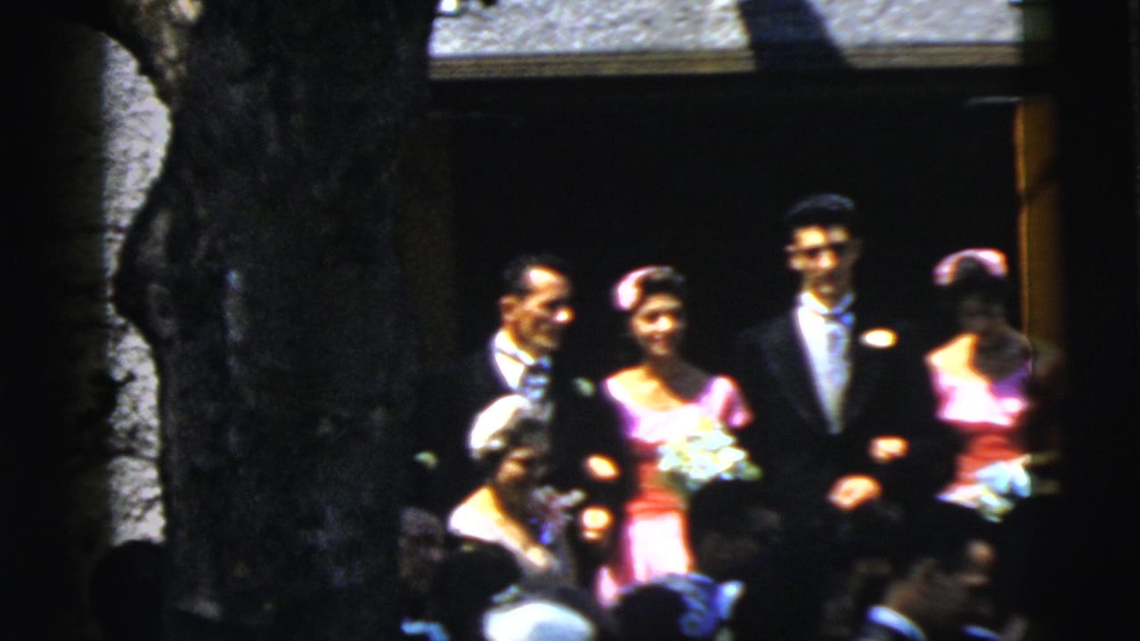 Wedding party standing outside a church doorway with guests in the foreground.