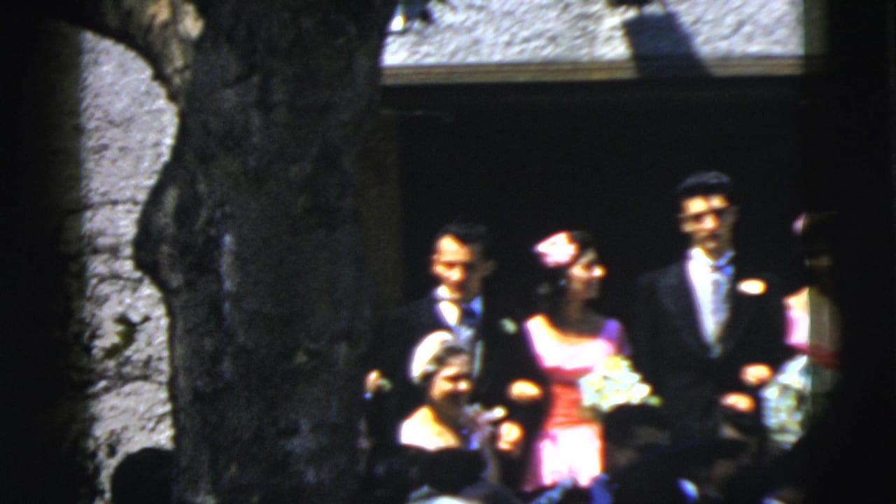 Bride, groom, attendants, and guests standing outside a church entrance.