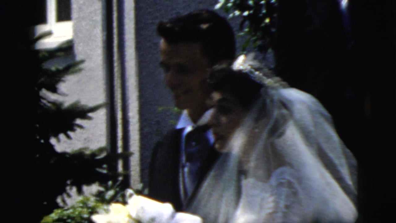 The bride and groom appear close together outside in Camden, New Jersey, with the bride's veil and bouquet visible in soft 8mm focus.