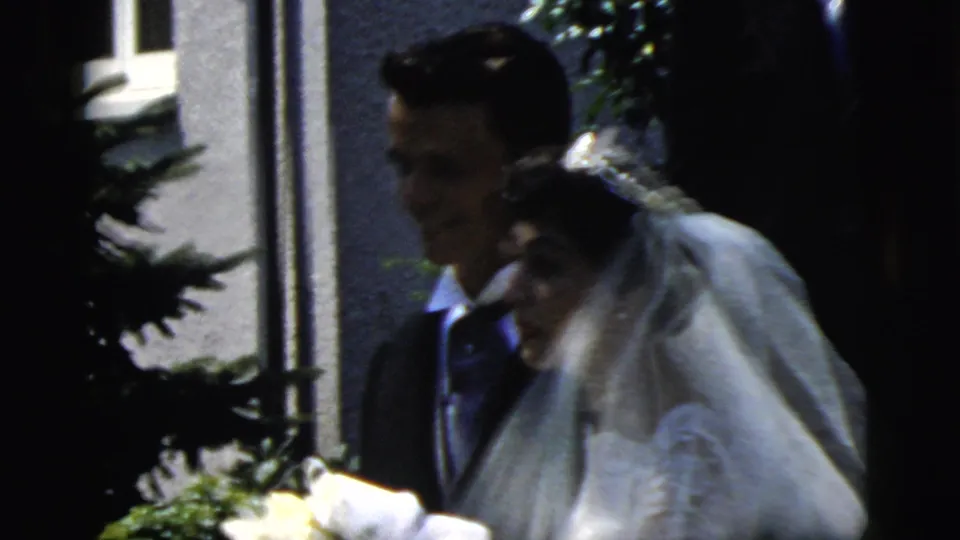 The bride and groom appear close together outside in Camden, New Jersey, with the bride's veil and bouquet visible in soft 8mm focus.