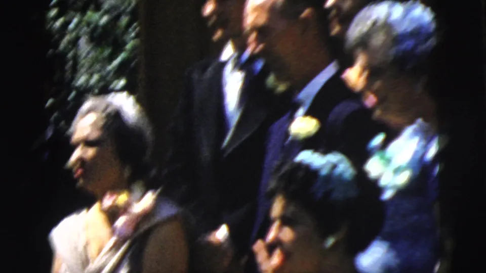 Wedding guests in 1961 Camden gather outdoors in suits and dresses, with corsages and floral accessories visible in the crowd.