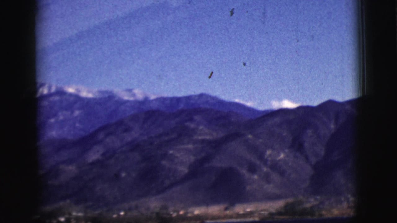 Distant Arizona mountains with possible snow-capped peaks, filmed from a vehicle in the 1961 home movie.