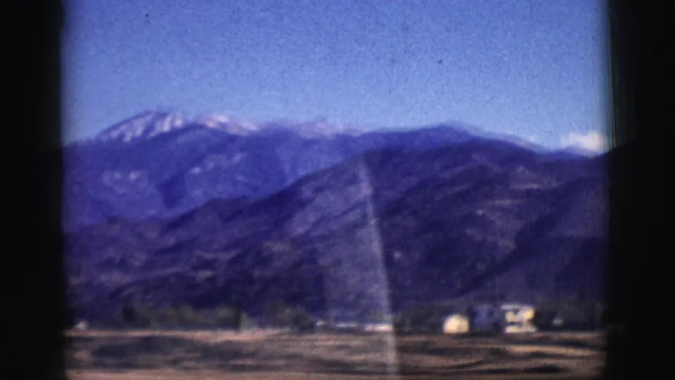 Clarkdale-area mountain scenery with a distant snowy summit, foreground ridges, valley structures, and visible film gate edges.
