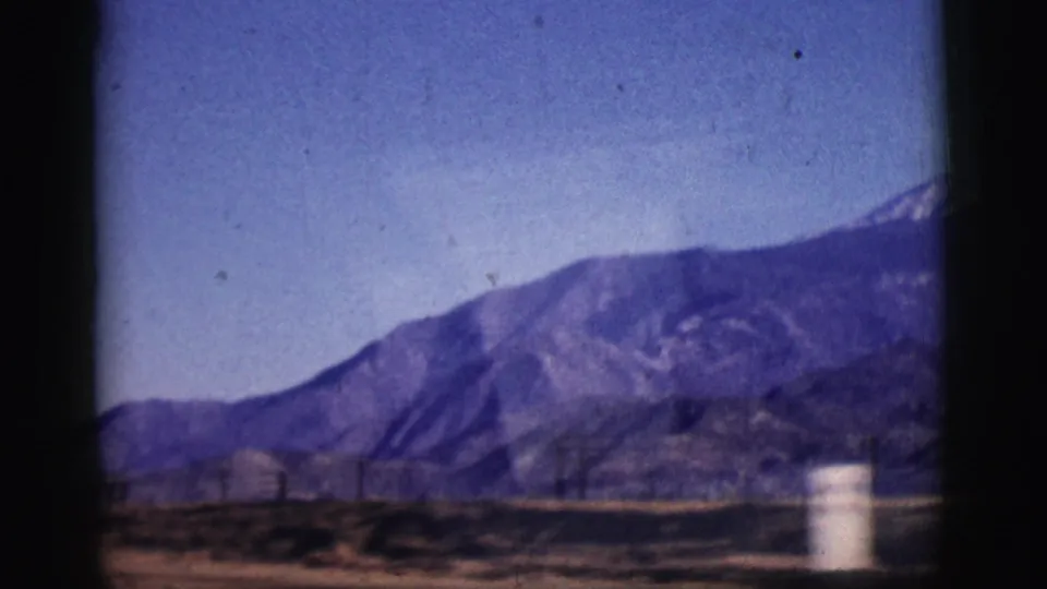 1961 Clarkdale, Arizona frame with a broad mountain slope, power lines, desert ground, and a white marker near the lower edge.