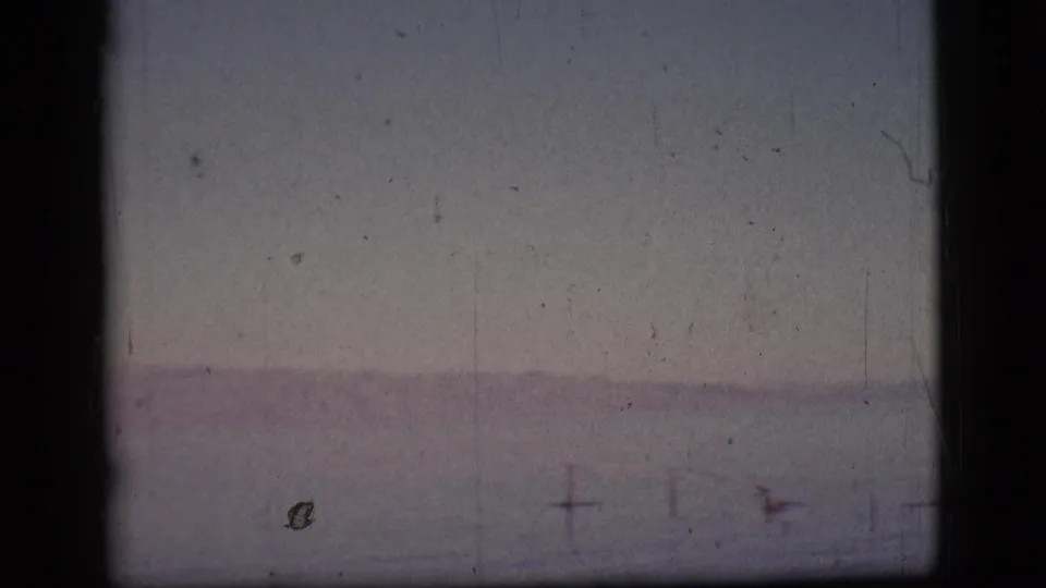 Faded 1961 8mm frame showing open water and a pale horizon, with dust and color shift visible in the scan.