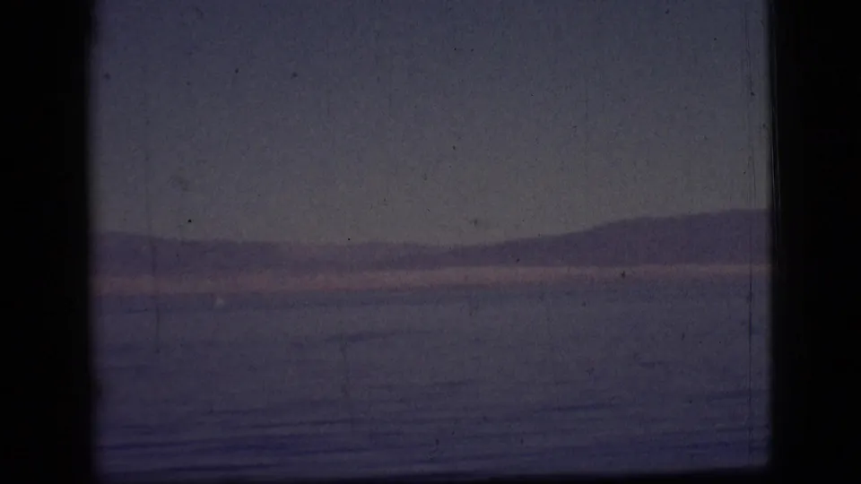 1961 8mm home-movie frame from the Clarkdale, Arizona metadata context showing calm water, distant mountains, and a dusky sky.
