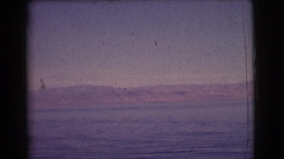 1961 8mm home-movie frame from Clarkdale, Arizona, showing calm lake water and distant hills under a purple-shifted sky.