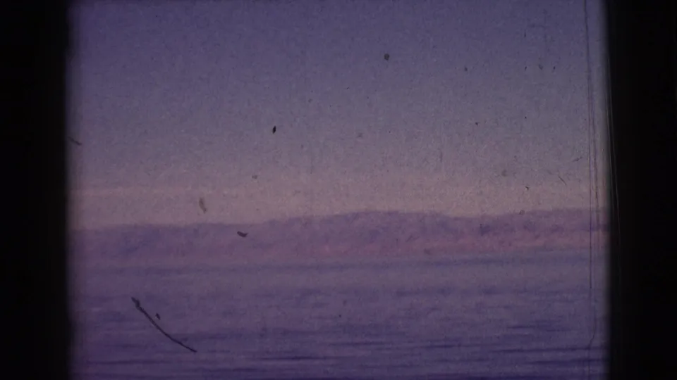 Clarkdale, Arizona 8mm frame showing a quiet lake horizon, low hills, and visible scratches from the scanned film.