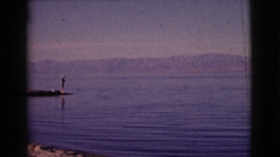 1961 Clarkdale, Arizona home-movie frame with a distant person standing on a small pier over a calm lake.