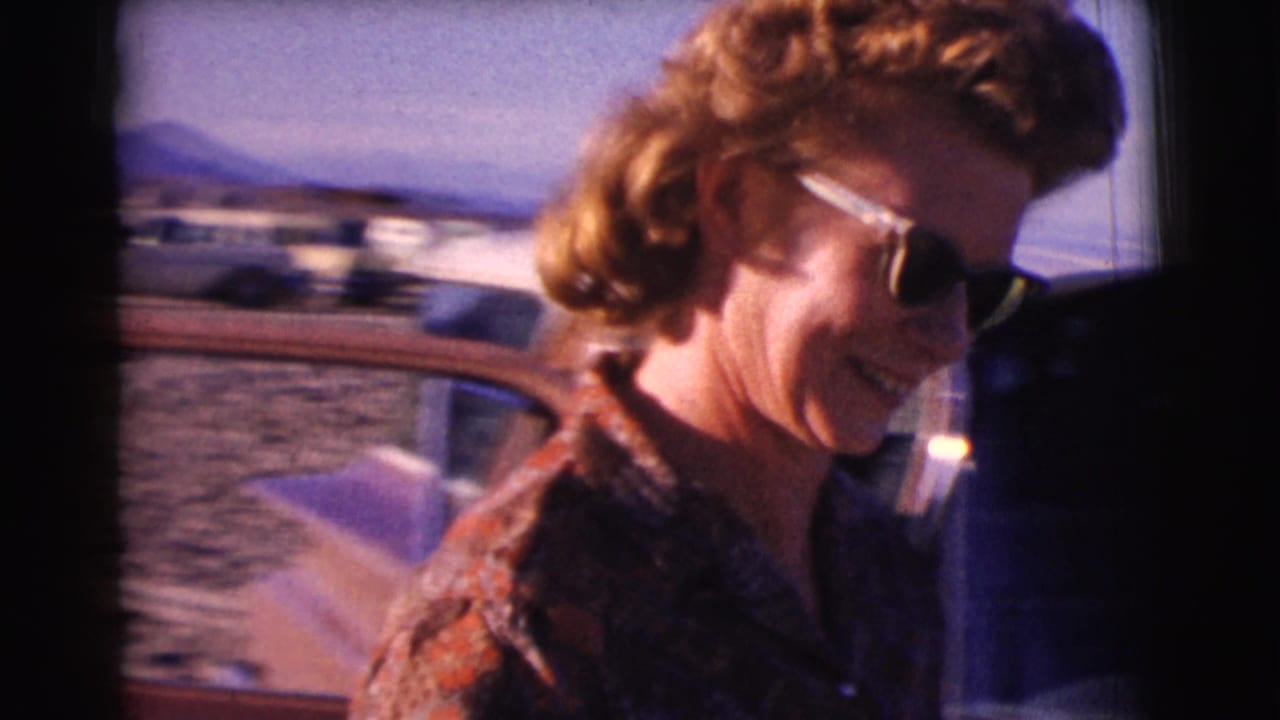 Woman in profile smiles beside a car with desert landscape in the background.