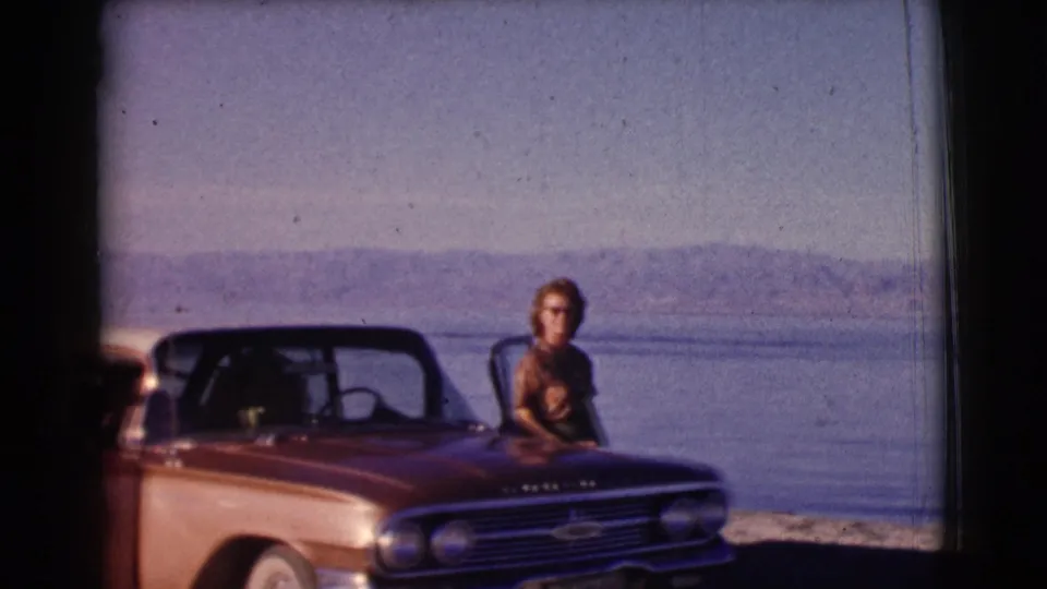 1961 Clarkdale, Arizona home-movie frame of a woman near the hood of a classic station wagon by the lake.