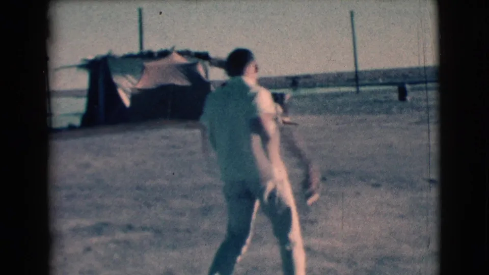 In Clarkdale, Arizona in 1961, a man in a white shirt and light trousers walks across dusty open ground near distant structures.