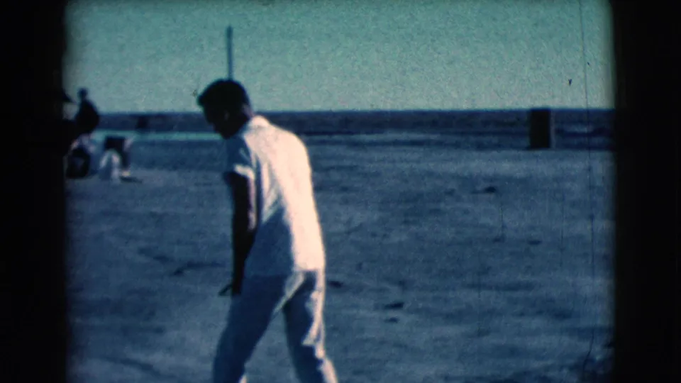 The man moves across the dusty Clarkdale ground, with distant objects and possible people near the horizon behind him.