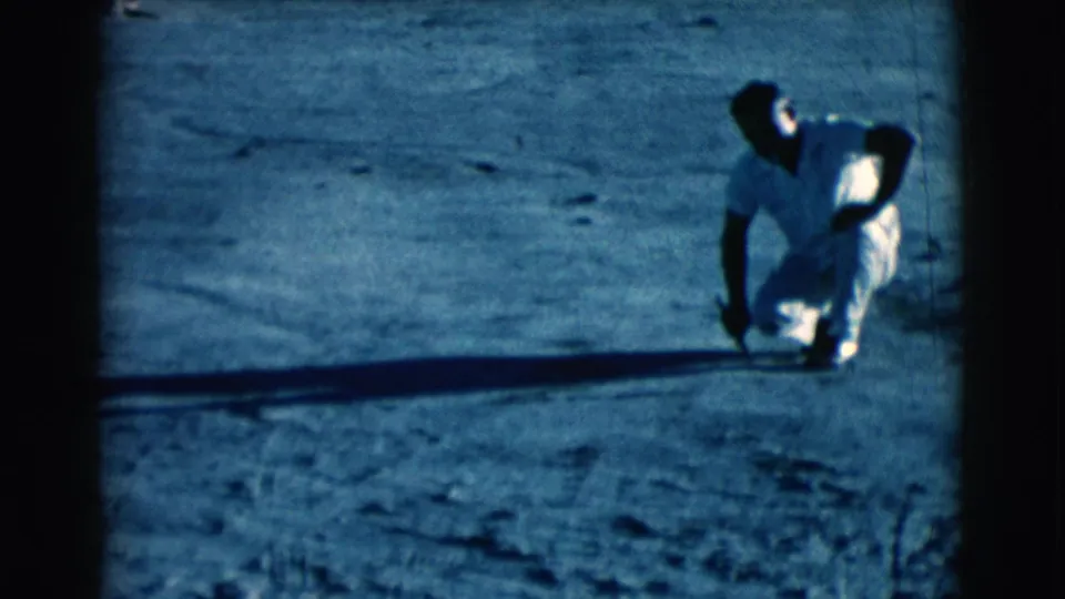 Near the end of the clip, the man crouches beside a long shadow on dusty Clarkdale ground while holding a stick or tool.