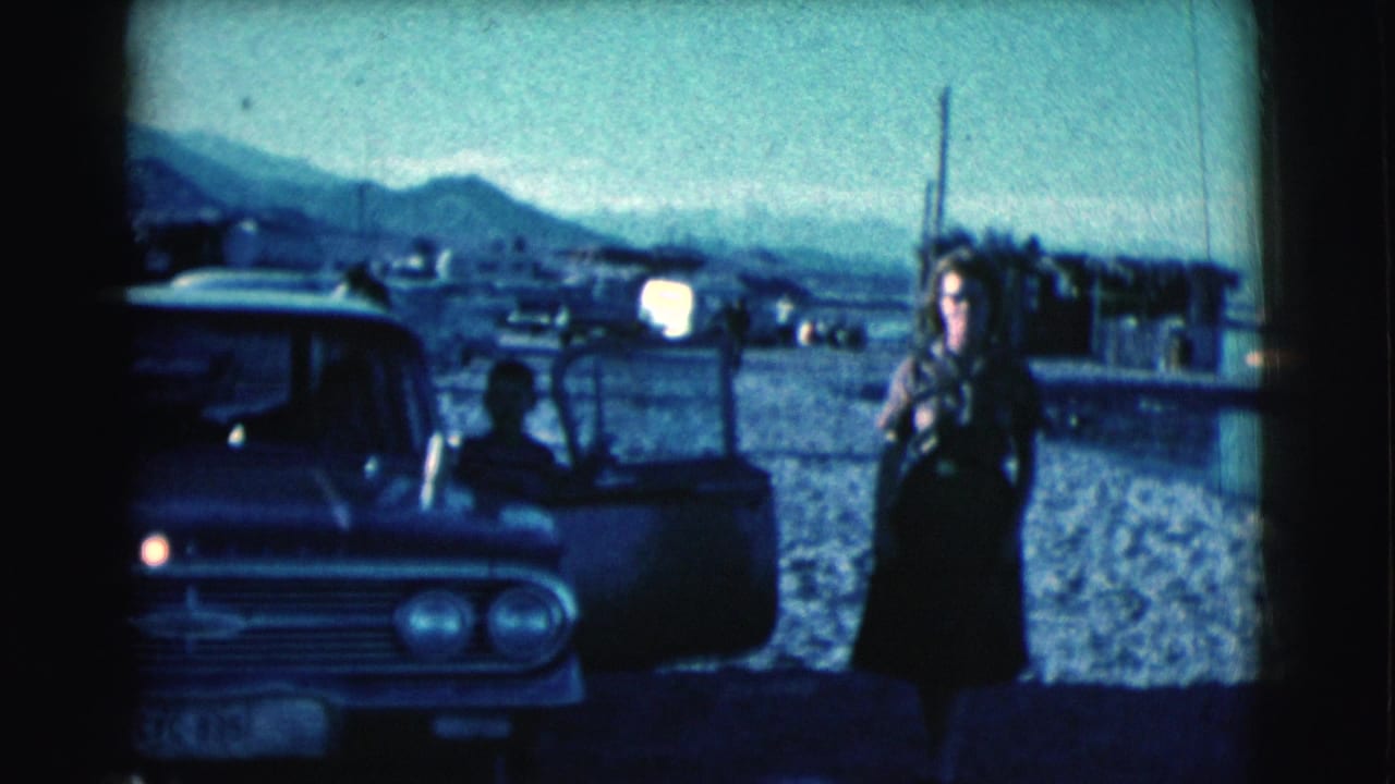 Woman walks away from a vintage car while a man is partly visible inside the open door.