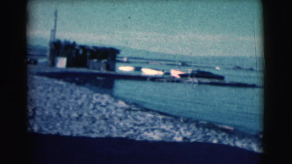 The clip ends on a Clarkdale waterfront view with gravel shoreline, calm water, a small dock or boat structure, and mountains beyond.