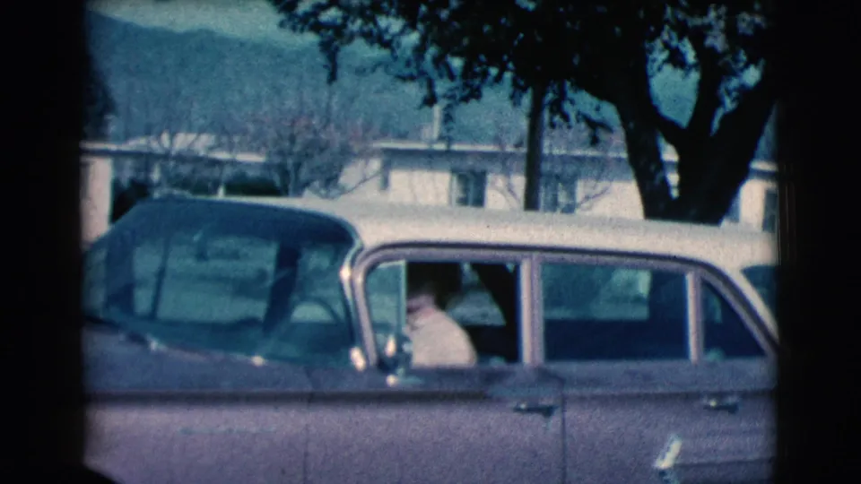 The final frame shows the person inside the vintage car, with the side window, tree canopy, parked car, and distant hills visible.