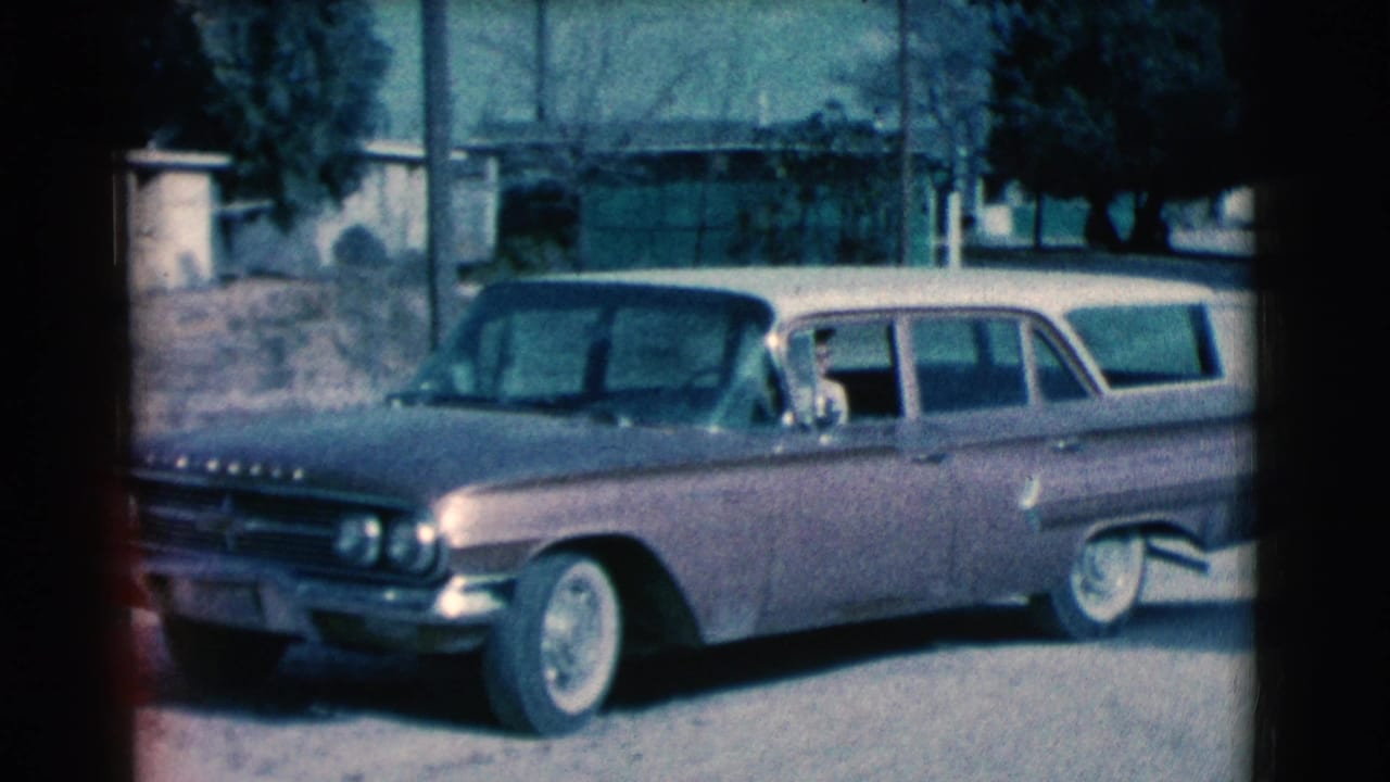 Light-colored station wagon backing from a residential driveway.