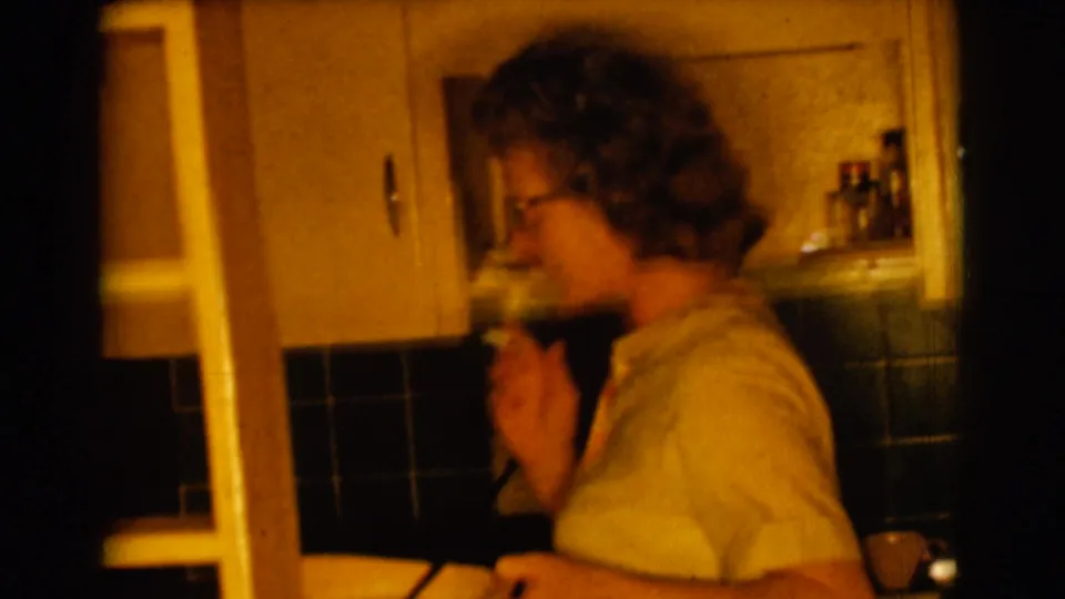 A woman in a yellow top stands by a kitchen counter in the Clarkdale home-movie interior.