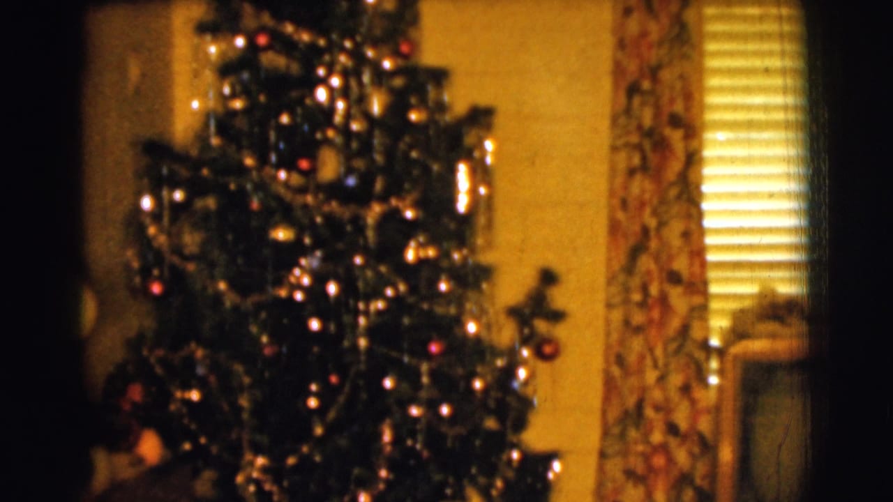 1961 Clarkdale, Arizona home-movie frame showing a decorated Christmas tree in a yellow-walled room with floral curtains and blinds.