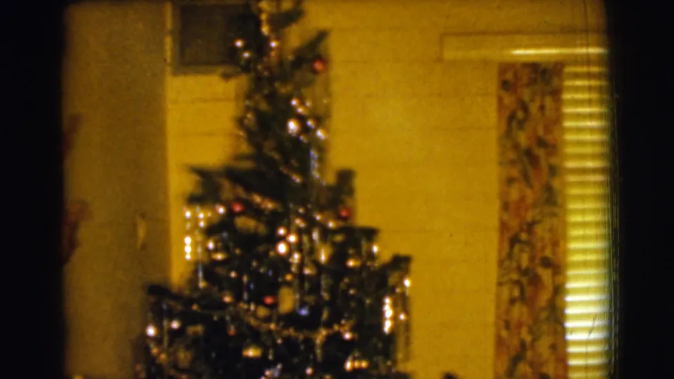 The 8mm frame shows the upper Christmas tree in a Clarkdale home interior, with ornaments, tinsel, floral curtains, and blinds.