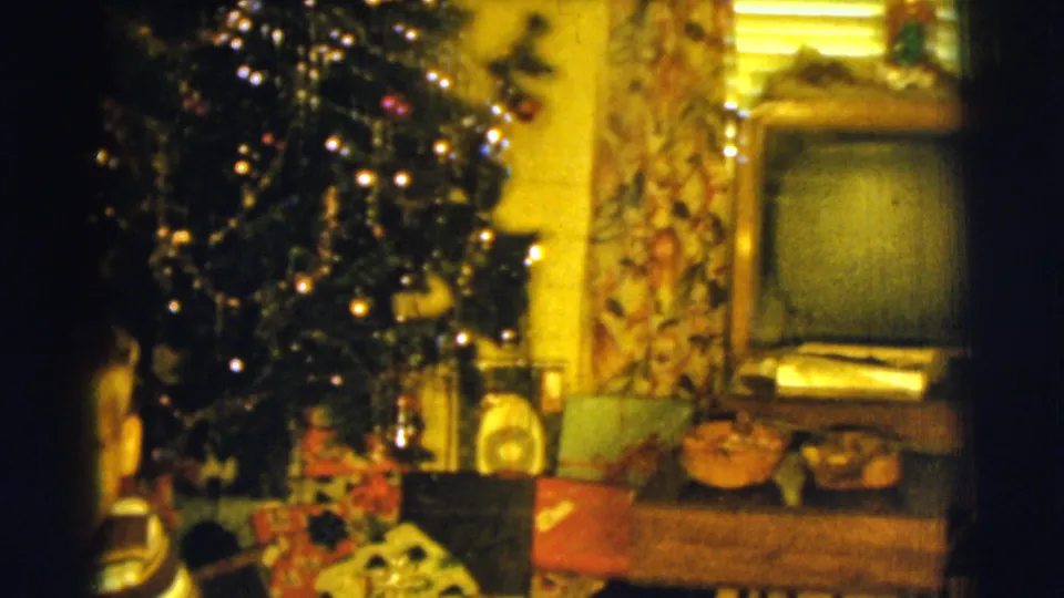 1961 Clarkdale frame showing a decorated Christmas tree beside wrapped gifts, floral curtains, and a mid-century console television.