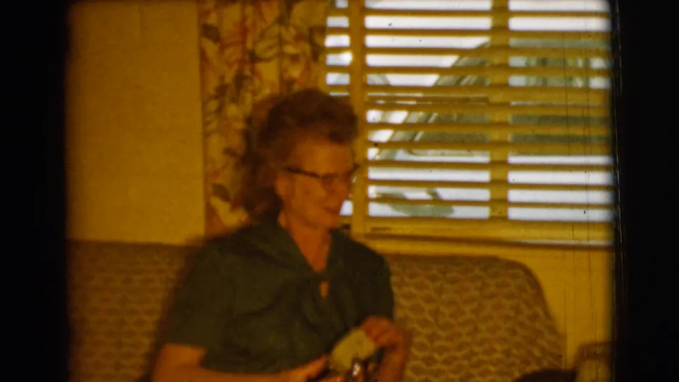 The final frame shows the woman on the couch in the Clarkdale home interior, with horizontal blinds, floral curtains, and a lamp in view.