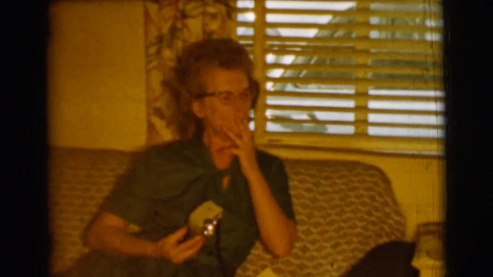 The woman appears to take a drag from a cigarette while seated on the sofa in the Clarkdale, Arizona interior.