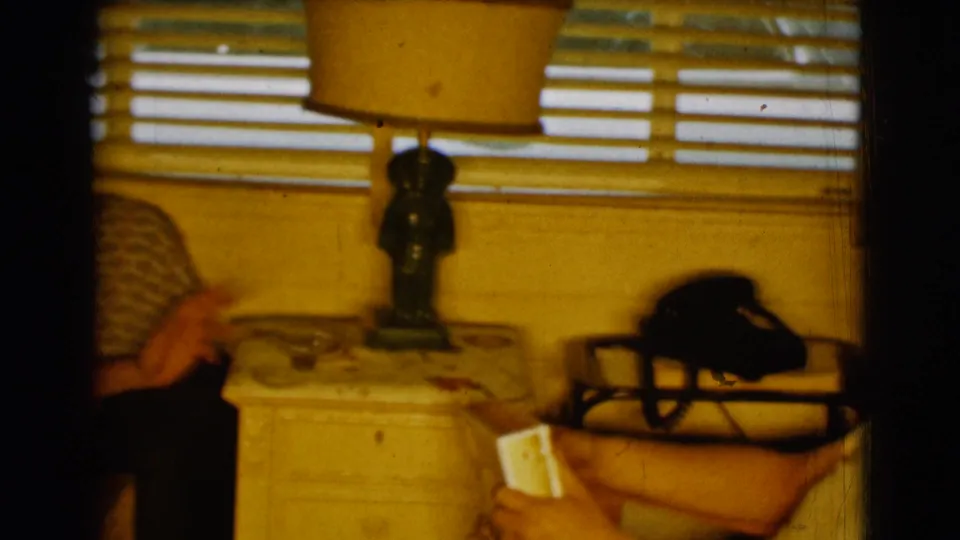 A 1961 Clarkdale, Arizona interior detail shows a side table, lamp, window blinds, sofa edge, tray, and black telephone.